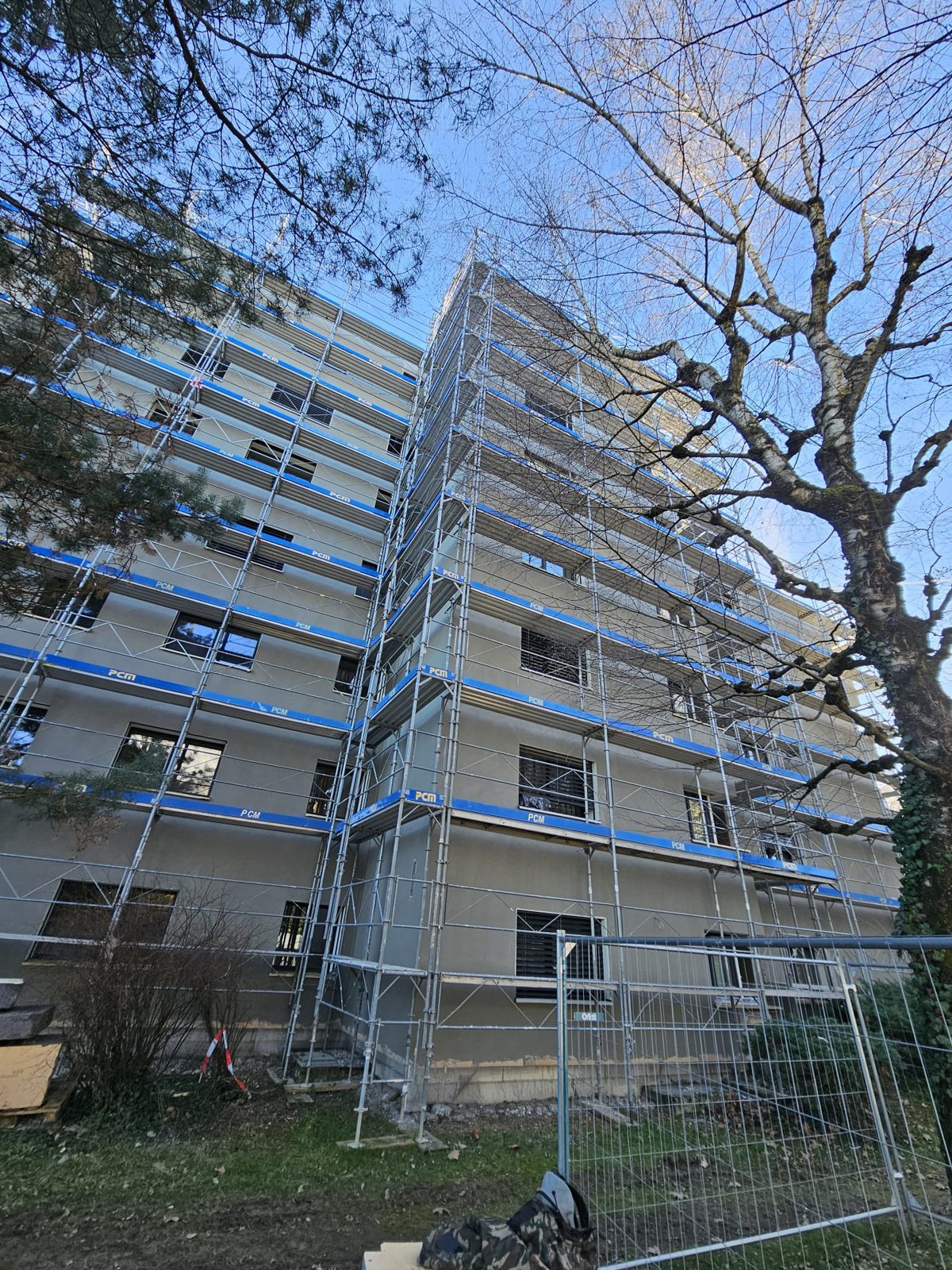 Échafaudages devant un immeuble bordé d’arbres