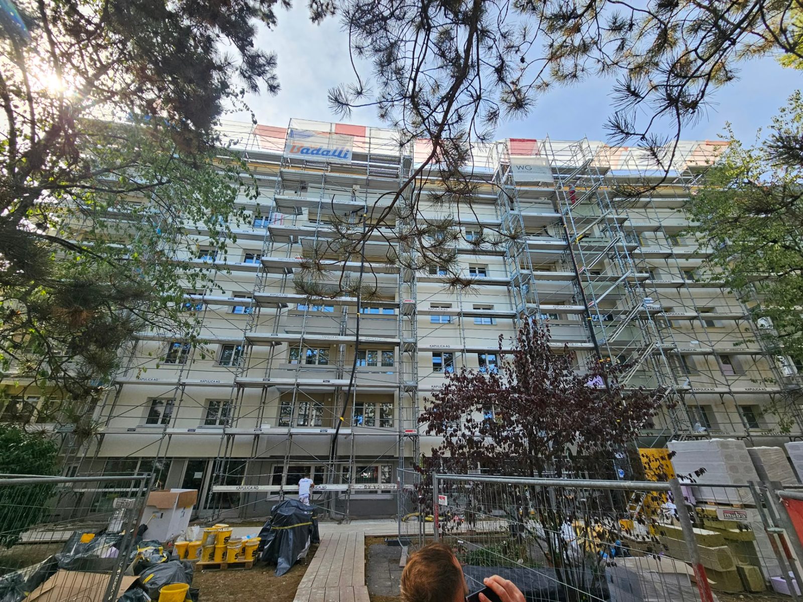 Longue façade en travaux vue depuis une rue arborée