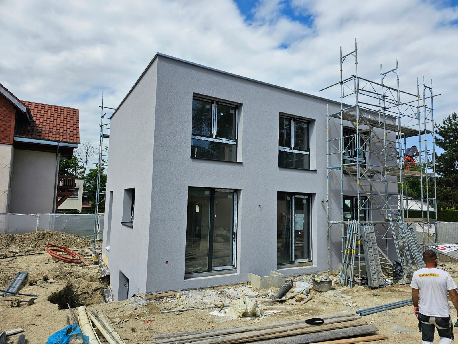 Maison à façade grise avec travaux sur le côté