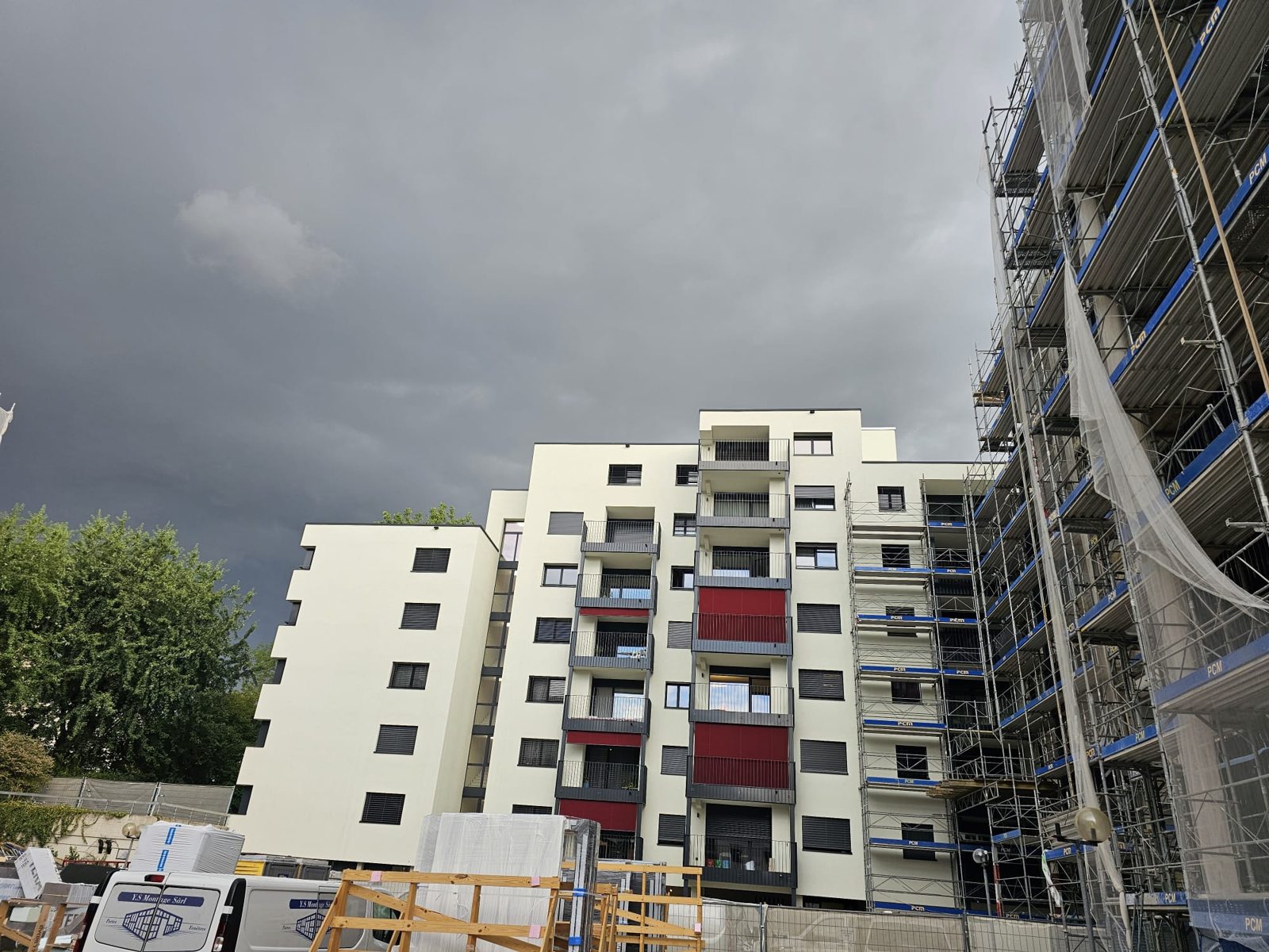 Immeuble avec balcons rouges à côté d’un chantier de façade